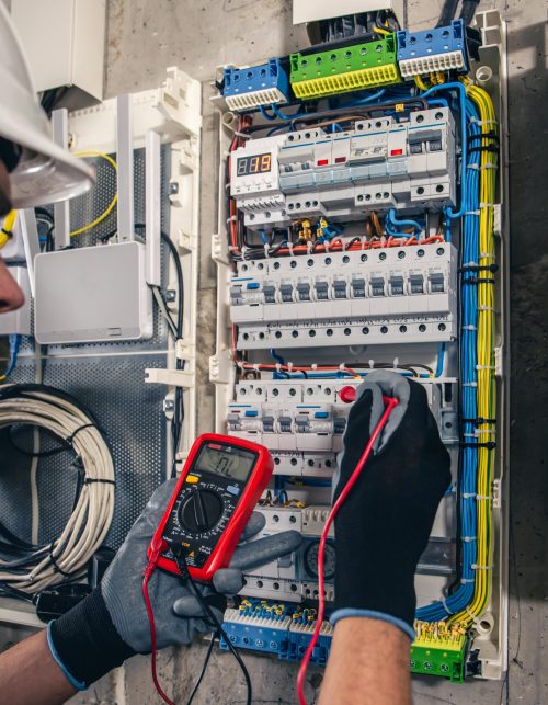 man-electrical-technician-working-switchboard-with-fuses-min
